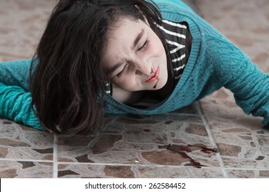 pretty young upset girl with a bleeding nose after falling down