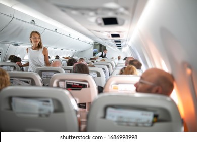 Pretty, young woman aboard an airplane during a lang haul commercial flight - stretching her legs a bit, walking in the aisle