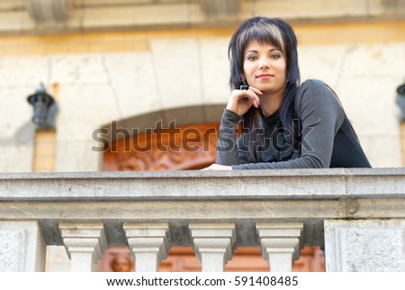 Pretty young woman in black dress on the balcony of luxury castle