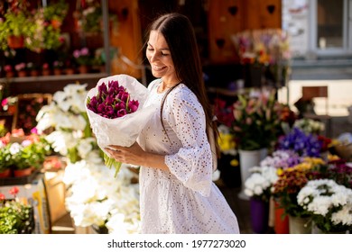 Pretty young woman buying flowers at the flower market - Powered by Shutterstock