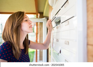 Pretty, young woman checking her mailbox for new letters