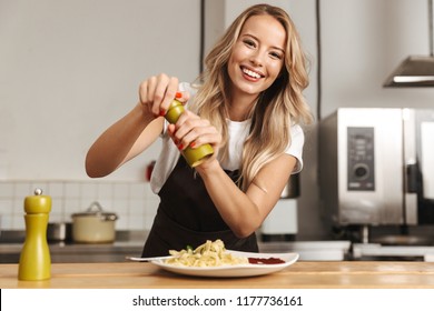 Pretty young woman chef putting salt in a pasta - Powered by Shutterstock