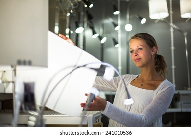 Pretty, young woman choosing the right light for her apartment in a modern home furnishings store (color toned image; shallow DOF)