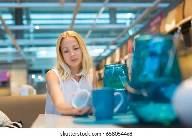 Pretty, Young Woman Choosing The Right Item For Her Apartment In A Modern Home Decoration Furnishings Store.