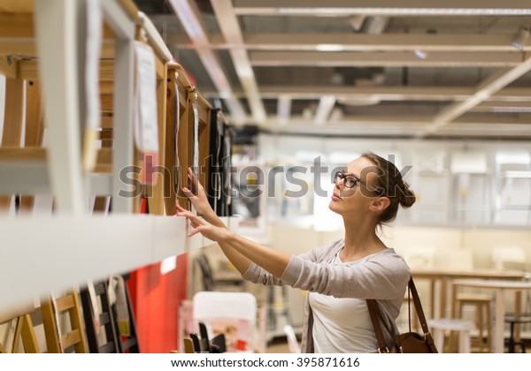 Pretty, young woman choosing the right furniture for\
her apartment in a modern home furnishings store (color toned\
image; shallow DOF)