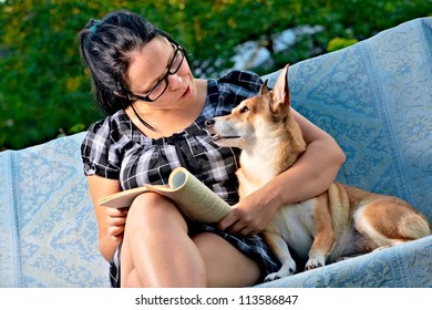 Pretty Young Woman With Dog Reading Magazine