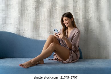 Pretty Young Woman In Dressing Gown Spending Leisure Time, Resting And Relaxing On Couch At Home Using Smartphone, Browsing Social Media, Liking Profile Of Man In Dating Application