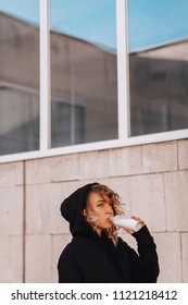 pretty young woman drinking bottle of milkwhile wearing in black hoodie