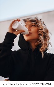 pretty young woman drinking bottle of milkwhile wearing in black hoodie