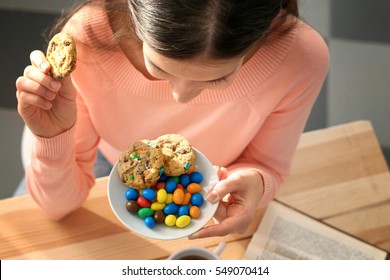 Pretty Young Woman Eating Tasty Cookies And Candies At Home