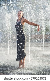 Pretty young woman  enjoy the cold water of  open street fountain in hot summer day