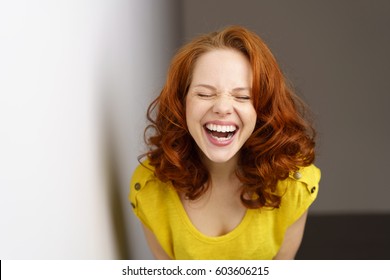 Pretty Young Woman Enjoying A Good Joke Having A Hearty Laugh With Mouth Open And Eyes Closed As She Leans Towards The Camera