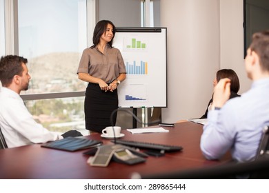 Pretty Young Woman Giving A Sales Pitch To A Group Of Business People In A Meeting Room