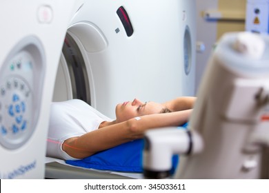 Pretty, young woman goiing through a Computerized Axial Tomography (CAT) Scan medical test/examination in a modern hospital (color toned image; shallow DOF)