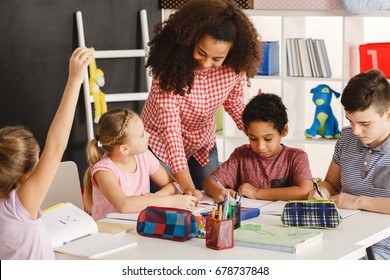 Pretty young woman helping kids with their homework