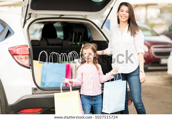 Pretty young woman with her daughter pulling the\
shopping bags in car\
boot
