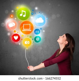 Pretty young woman holding colorful social media icons balloon