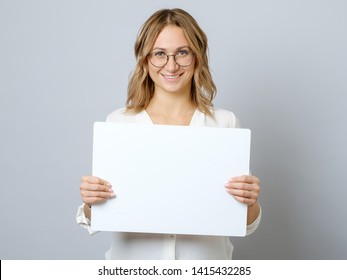 Pretty young woman holding empty blank board isolated on the gray background