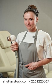 A Pretty Young Woman Holds A Maniple From A Laser Hair Removal Machine In Her Hands