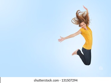 Pretty Young Woman Jumping For Joy On Blue Background