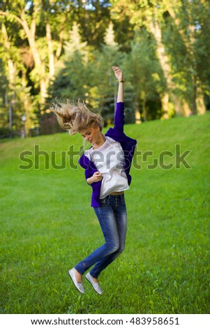 Pretty young woman jumping on green grass in the park