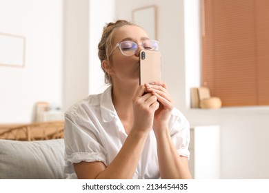 Mujer muy joven besando su teléfono móvil en casa