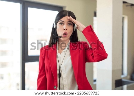 pretty young woman looking happy, astonished and surprised. telemarketer concept