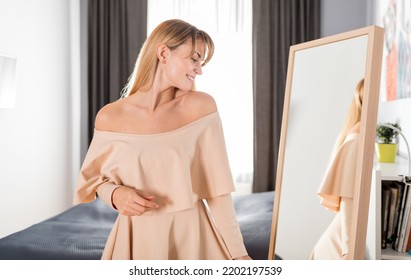 Pretty Young Woman Looks At Her New Outfit In Front Of A Mirror At Home