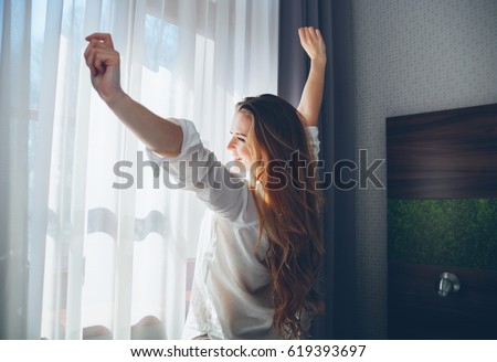 Pretty young woman in modern apartment stretching after wake up