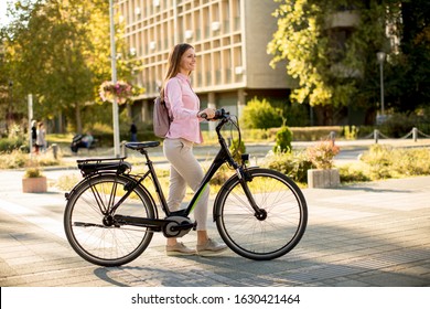 Pretty young woman and modern city electric e  bike clean sustainable urban transportation