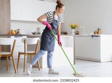 Pretty young woman mopping floor in light kitchen - Powered by Shutterstock