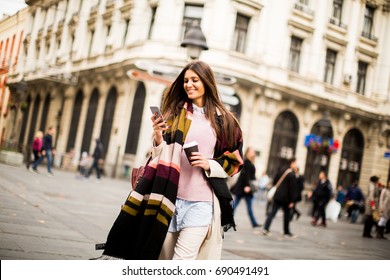 Pretty Young Woman On The Street With Coffee Cup And Mobile Phone At Autumn Day