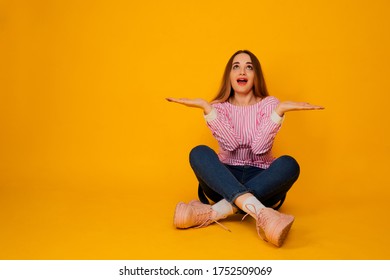Pretty young woman on stylish pink t-shirt and jeans sitting  isolated over yellow background.  - Shutterstock ID 1752509069