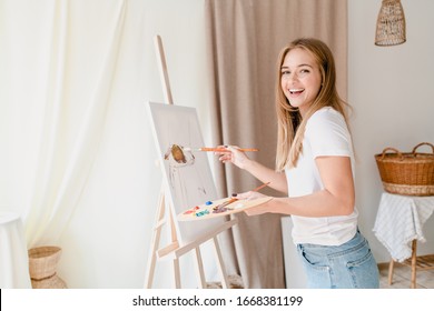 pretty young woman painting a picture on canvas in studio workshop - Powered by Shutterstock