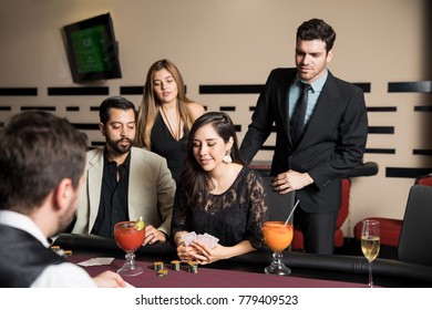 Pretty Young Woman Playing A Good Poker Hand At A Casino While Her Friends Stand Next To Her And Support Her