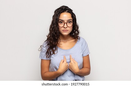 Pretty Young Woman Pointing To Self With A Confused And Quizzical Look, Shocked And Surprised To Be Chosen