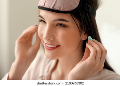 Pretty Young Woman Putting Blue Ear Plugs In Bedroom, Closeup