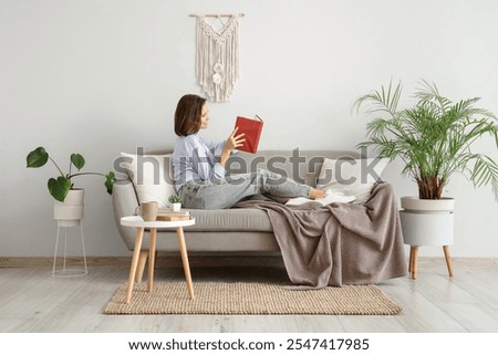 Similar – Image, Stock Photo Pretty young woman reading book and drinking morning coffee at home sitting at the window behind which there is an autumn landscape