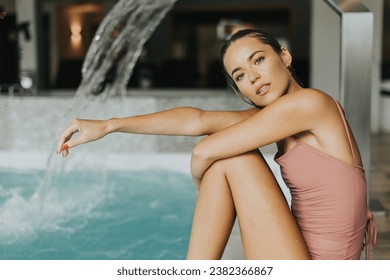 Pretty young woman relaxing by the indoor swimming pool - Shutterstock ID 2382366867