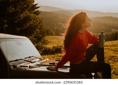 Pretty young woman relaxing on a terrain vehicle hood at countryside - Shutterstock ID 2290631583