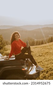 Pretty young woman relaxing on a terrain vehicle hood at countryside - Shutterstock ID 2314952675