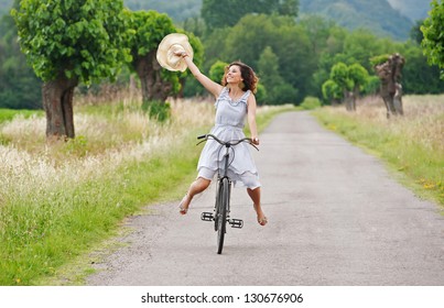 Pretty Young Woman Riding Bike In A Country Road.