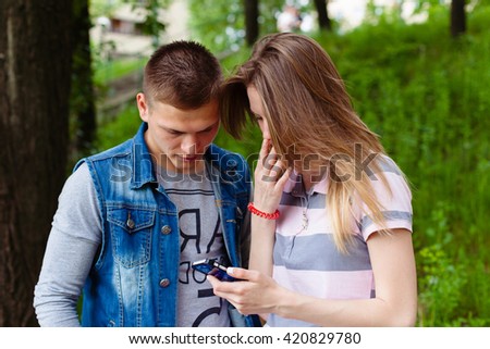 pretty young woman showing to her boyfriend best friend man something interesting in her smartphone. smile. outdoors, spring, summer