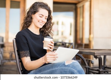 Pretty young woman sitting at coffee shop and using digital tablet - Shutterstock ID 1073366249