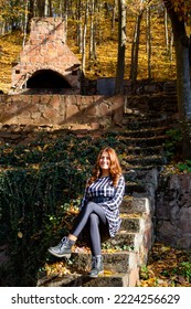 Pretty Young Woman Is Sitting On The Stairs At Sunset In Beautiful Autumn Forest. Colorful Autumn Landscape With Alone Girl And Fall Leaves. Travel And Adventure In Europe. Grza, Serbia.