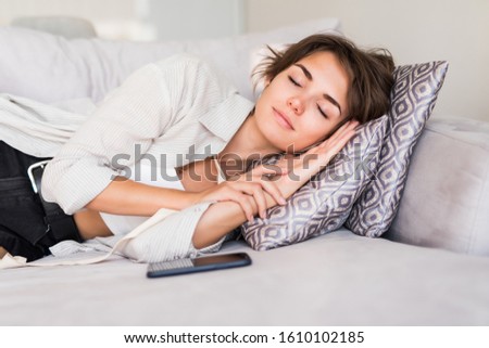 Pretty young woman sleeping with phone on couch at home