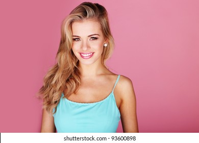 Pretty young woman smiling against a pink background