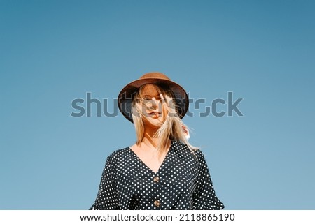 Similar – Porträt einer blonden Frau mit Hut, Sonnenbrille und roten Lippen, die bei Sonnenuntergang die Natur genießt.