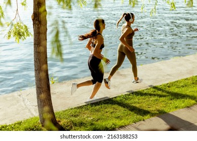 Pretty young woman taking running exercise by the river promenade - Powered by Shutterstock