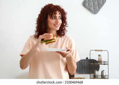 Pretty young woman with tasty sandwich in kitchen - Powered by Shutterstock